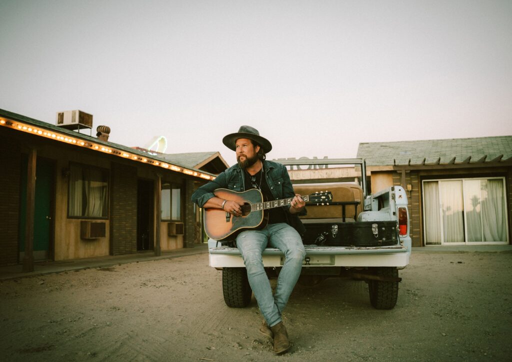 Zach Williams with the guitar sitting on the truck